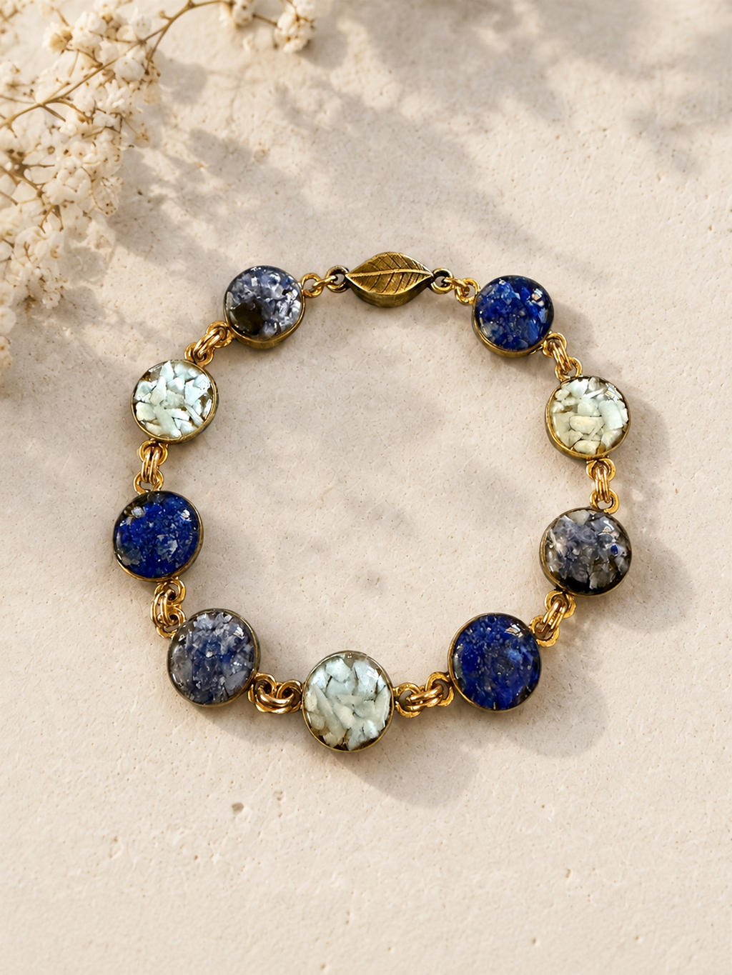 Blue crushed gemstone bracelet with a magnetic clasp, lapis lazuli, sodalite, and larimar set in resin, styled with dried flowers by June & Simple