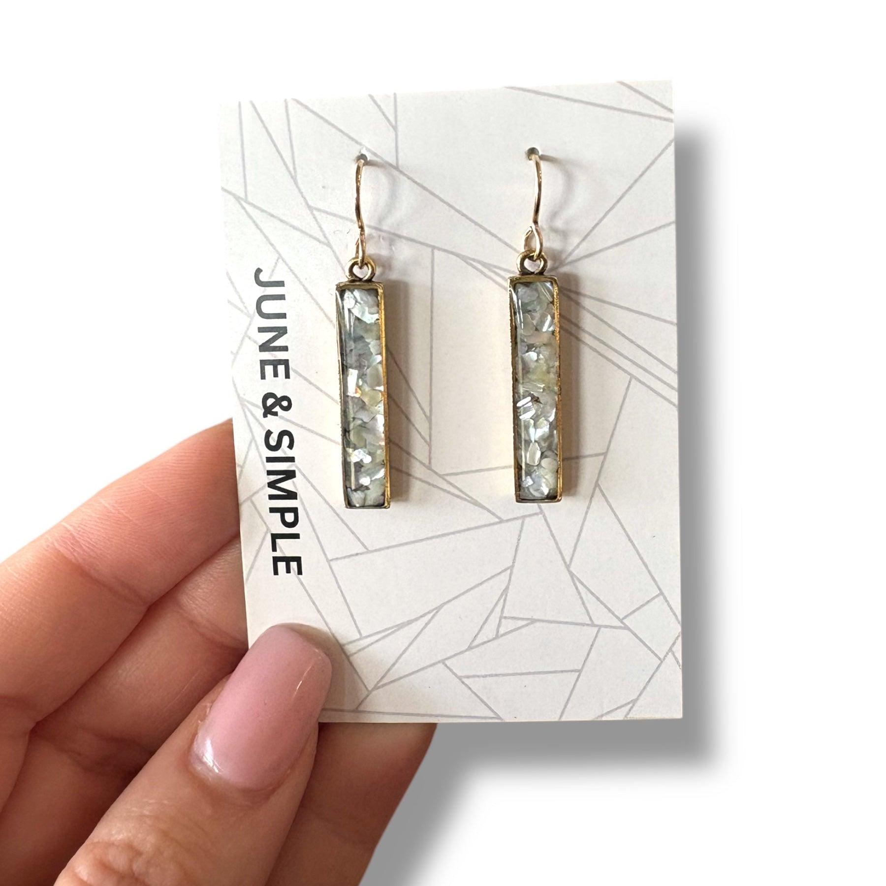 Pair of earrings on a 'June & Simple' branded card held by a hand.