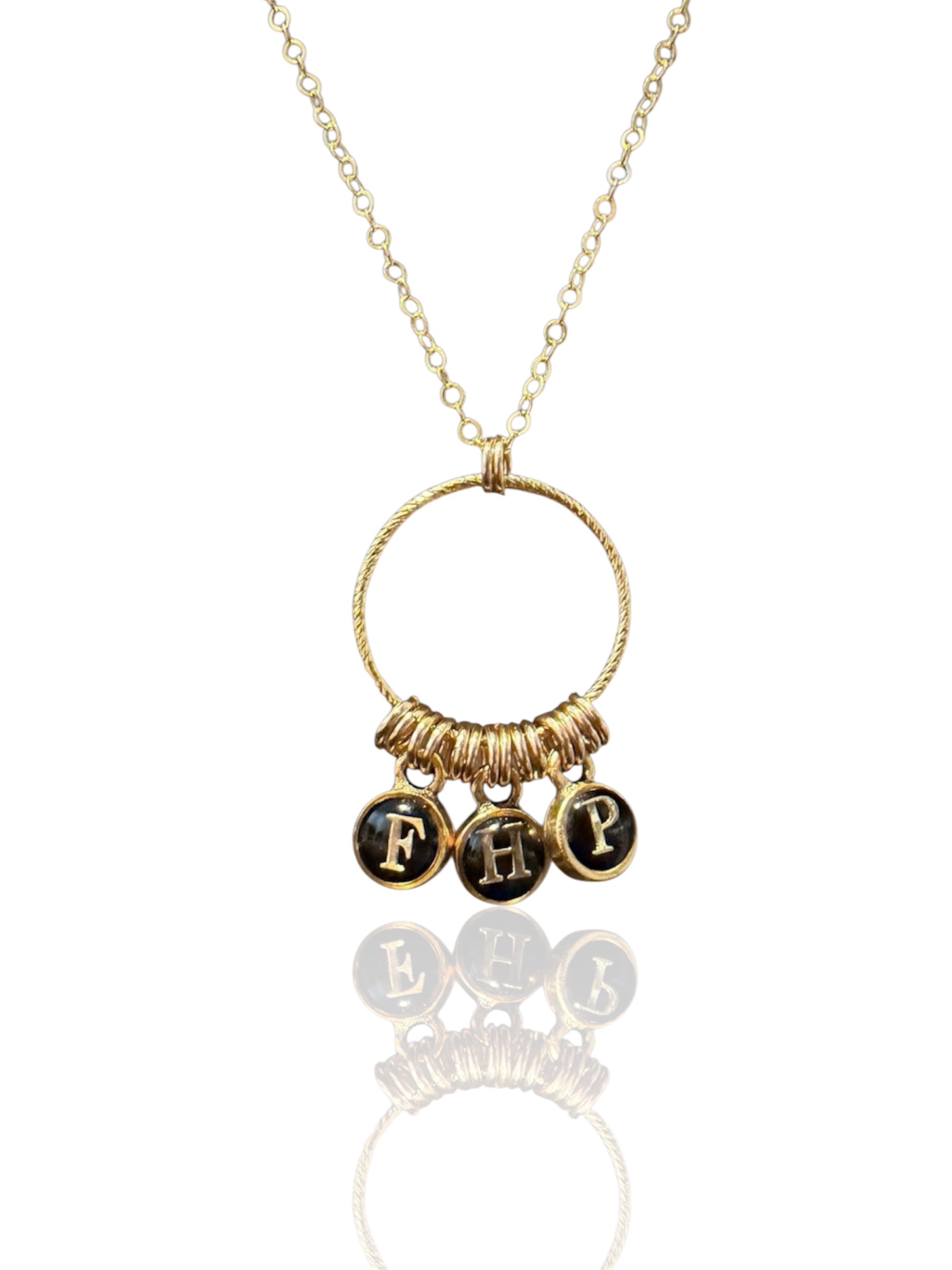 Build-your-own initial necklace with three typewriter-style letter charms on a gold ring pendant, shown on white