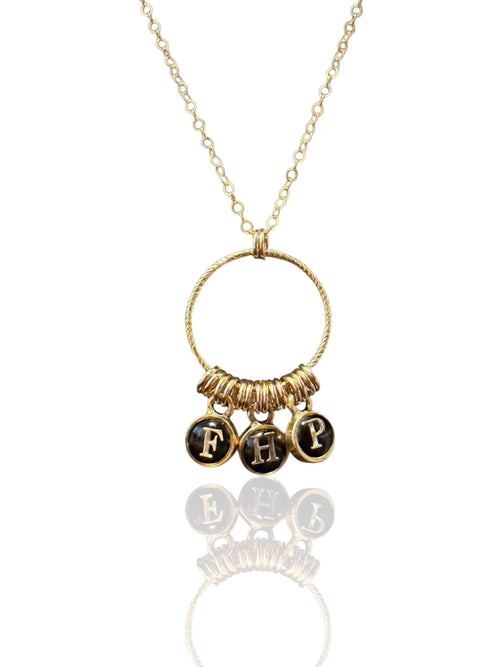 Build-your-own initial necklace with three typewriter-style letter charms on a gold ring pendant, shown on white