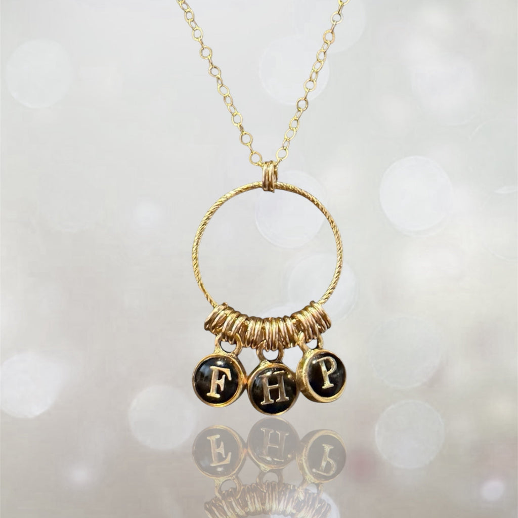 Personalized letter charm necklace with three initials on a gold-filled chain, soft light background