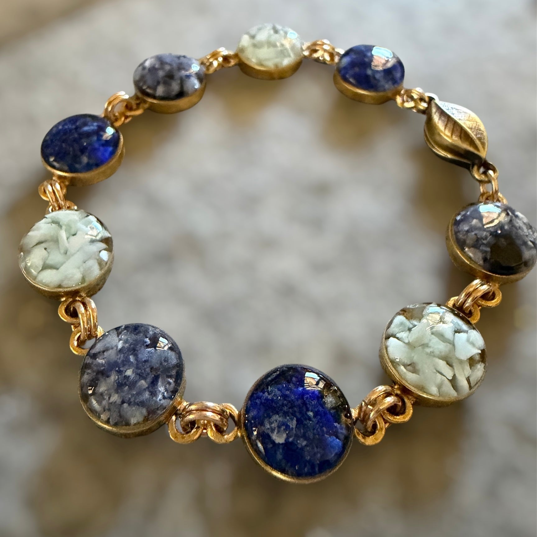 Close-up of the blue crushed gemstone bracelet, lapis lazuli, sodalite, and larimar set in resin, with the magnetic leaf clasp, by June & Simple
