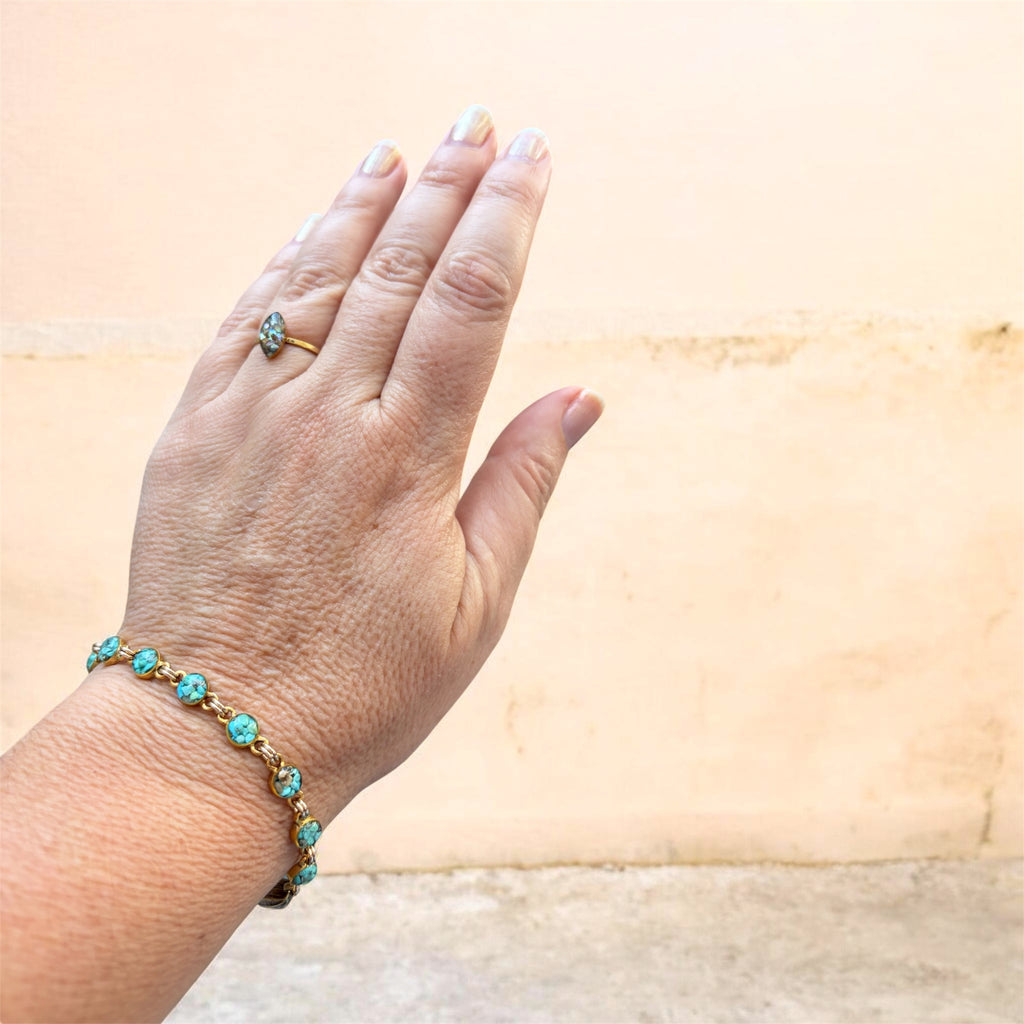 Small turquoise crushed gemstone bracelet worn on the wrist against a warm peach wall, handmade by June & Simple