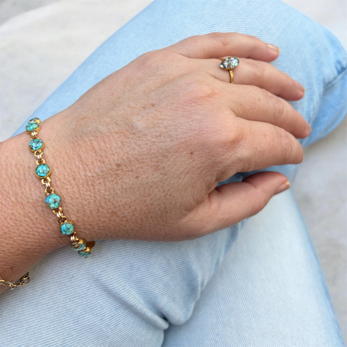Small turquoise crushed gemstone bracelet worn on the wrist, round turquoise settings in gold filled links, with a crushed abalone ring, handmade by June & Simple